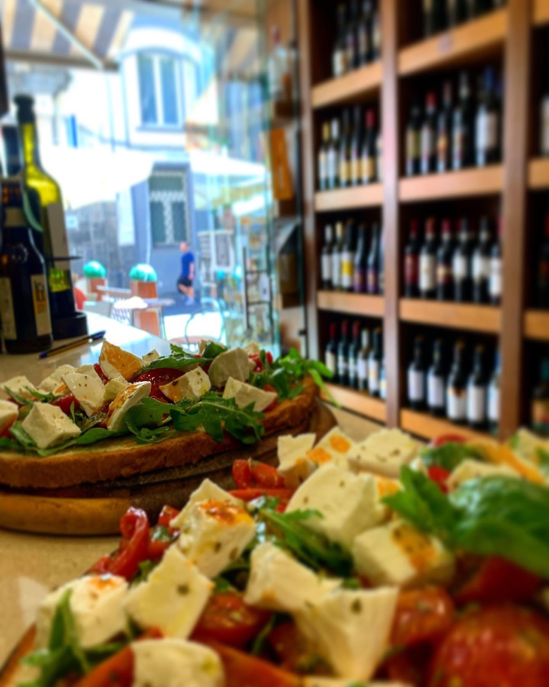 Caprese e bruschette davanti agli scaffali dei vini